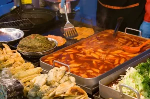 Korean street food market stall serving hot tteokbokki, savory pancakes and fried snacks