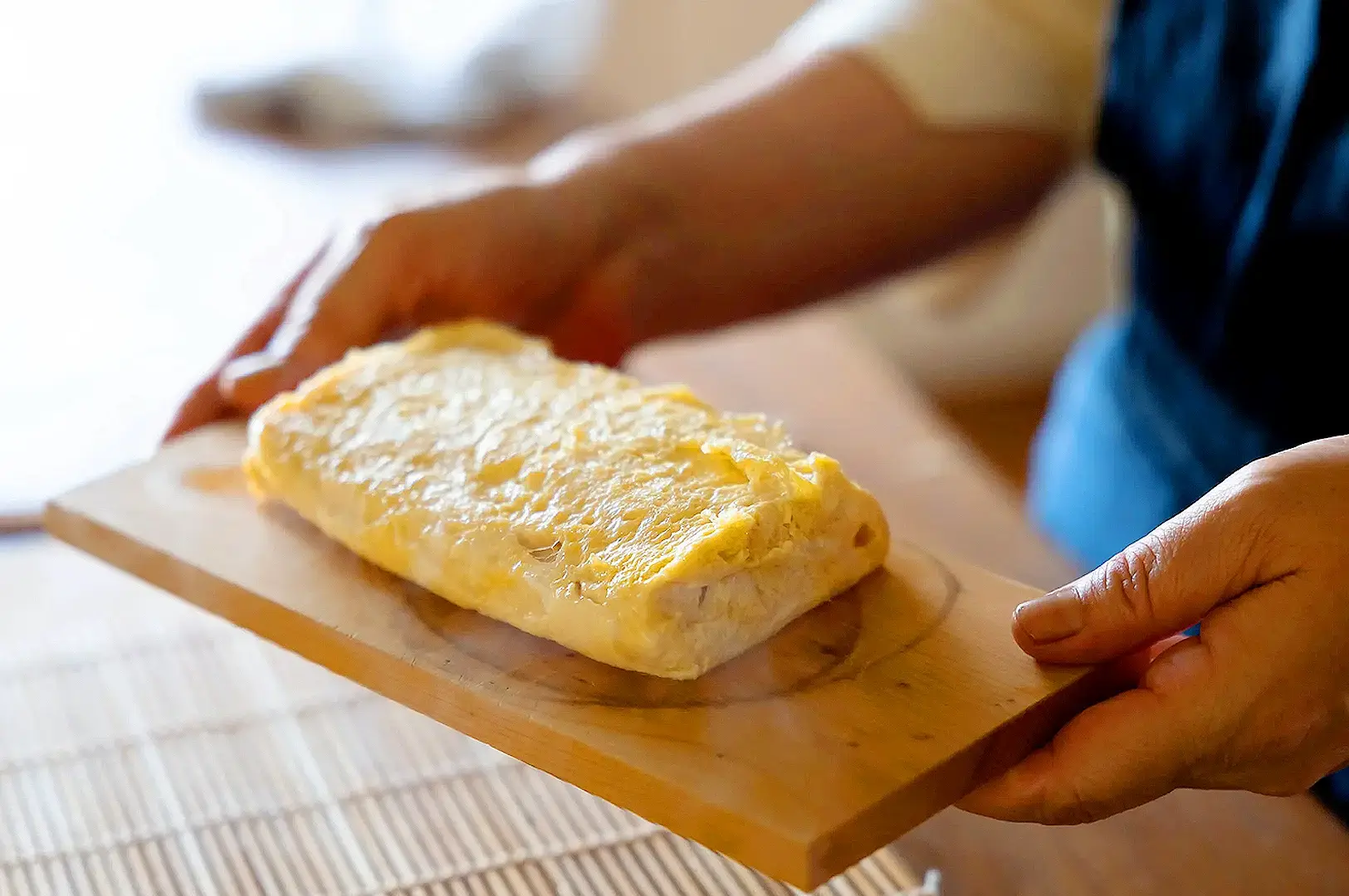 Homemade dashimaki tamago Japanese rolled omelette being prepared and shaped on a wooden cutting board