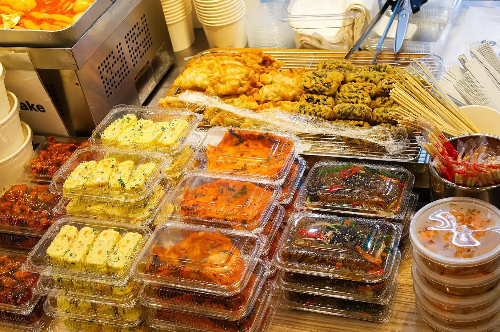 Korean street food stall with tteokbokki, fried snacks, kimbap and packaged side dishes