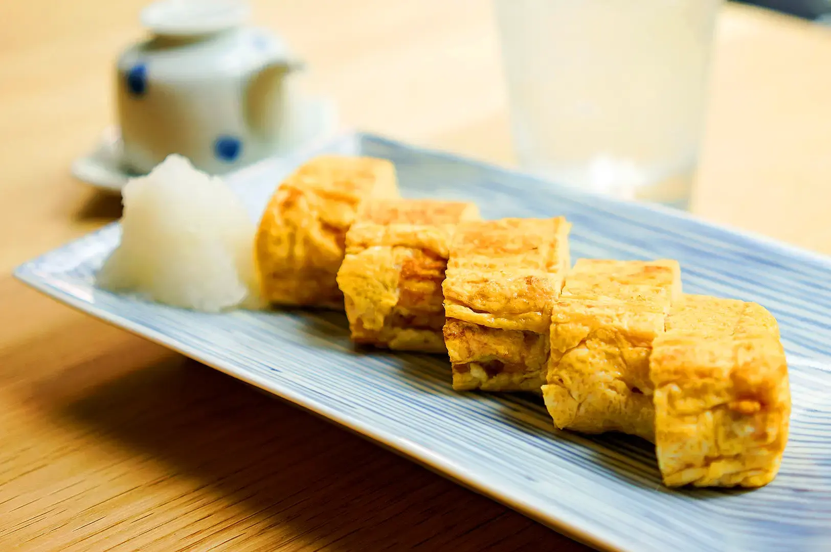 Dashimaki tamago Japanese rolled omelette slices served with grated daikon and traditional Japanese tea